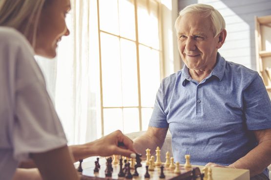 Smiling man playing chess with a young lady