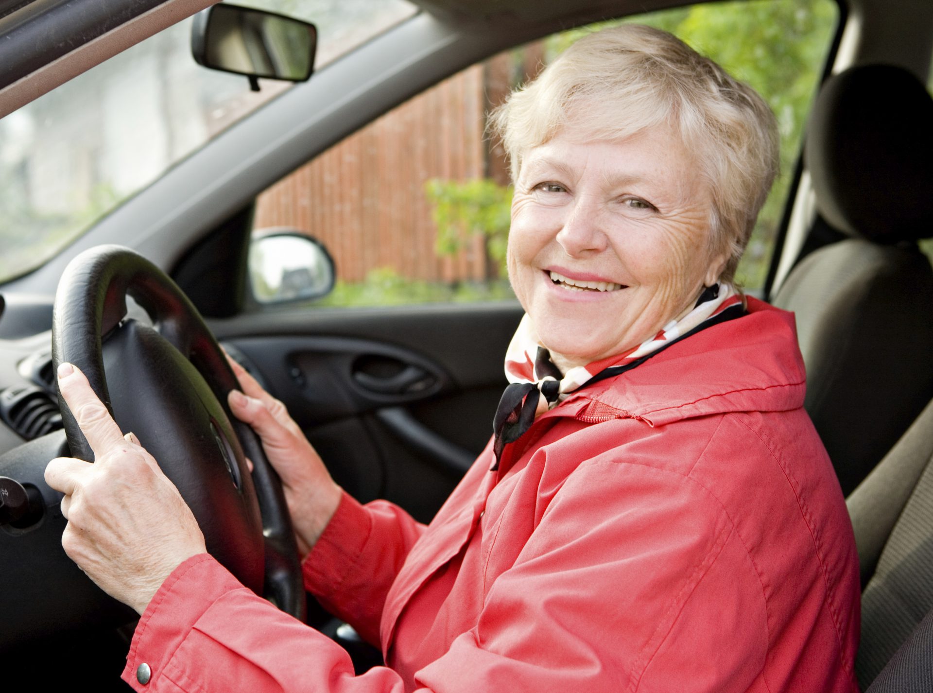 Smiling lady driving a car posing for the camera