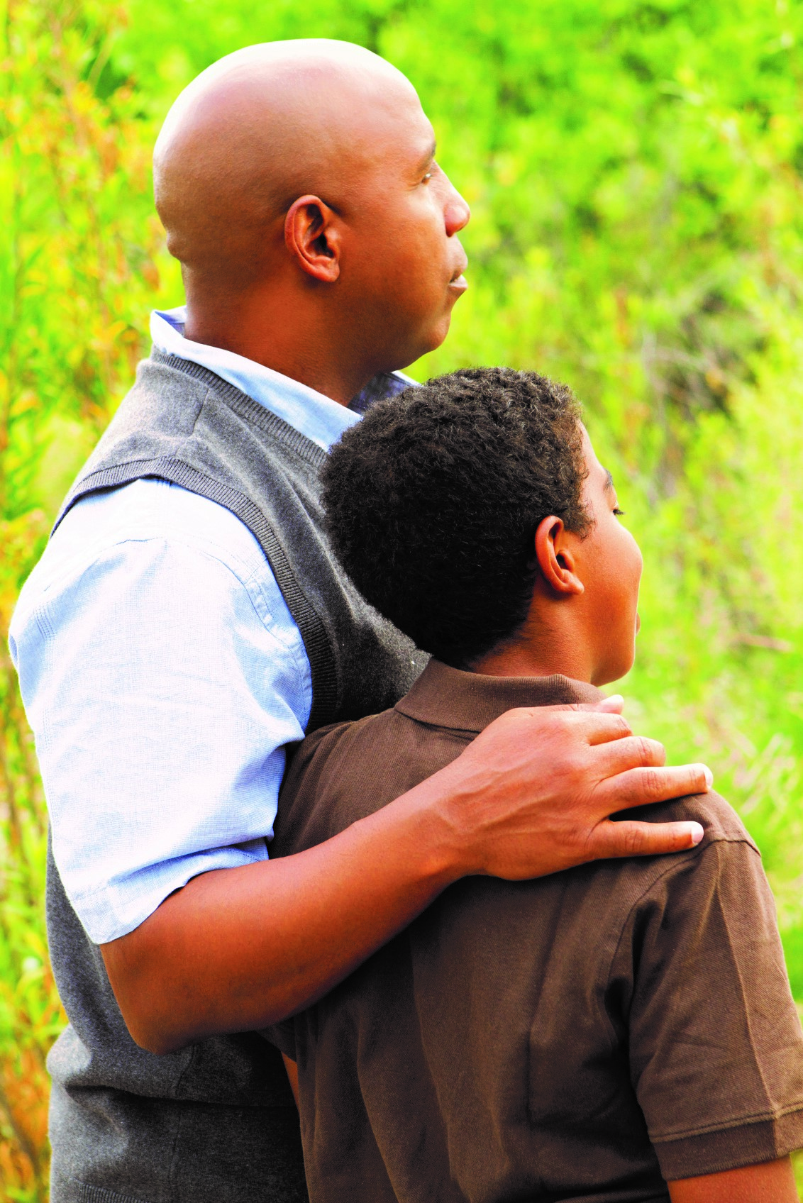 Father embracing his son looking at a lush green forest