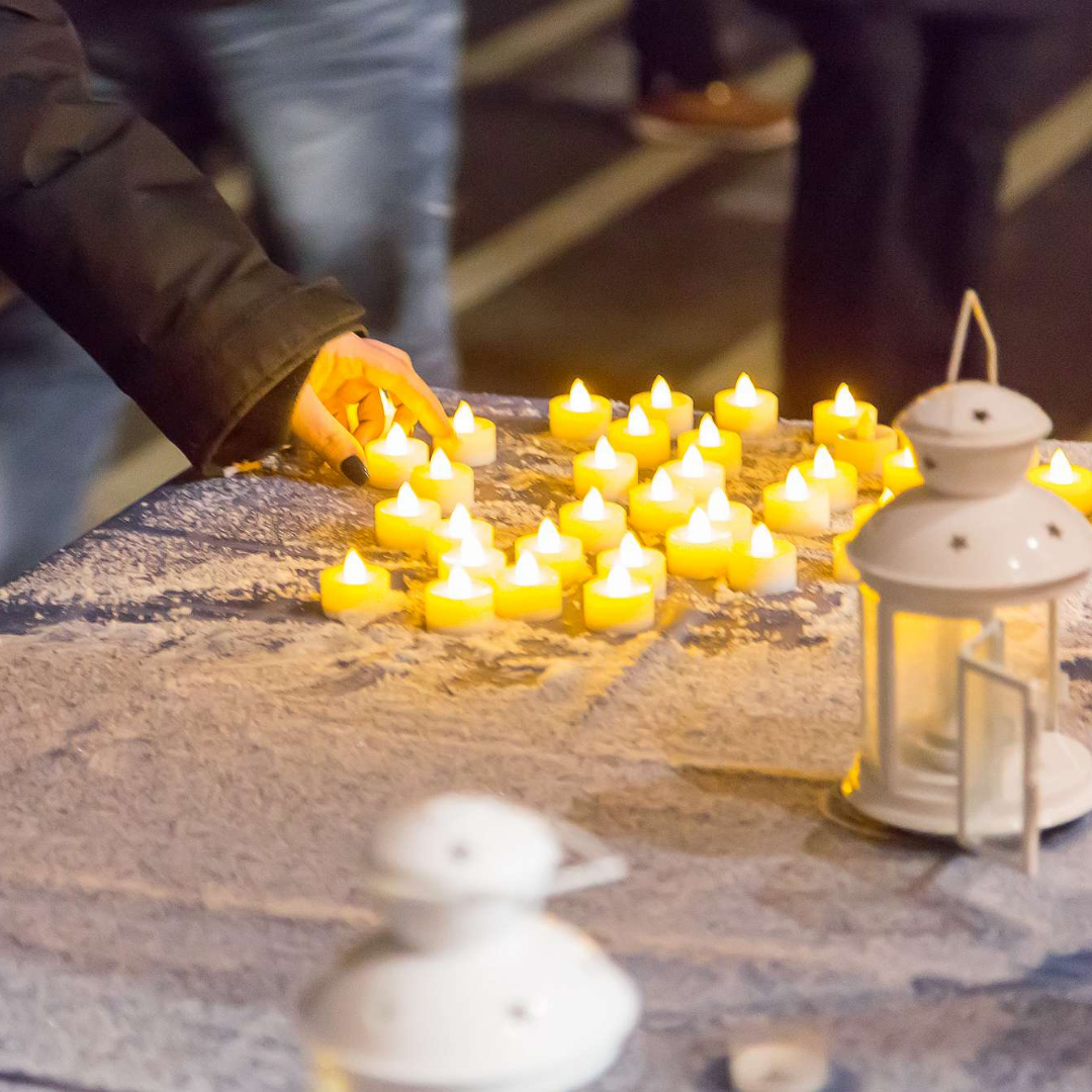 A person placing a tea light on a table