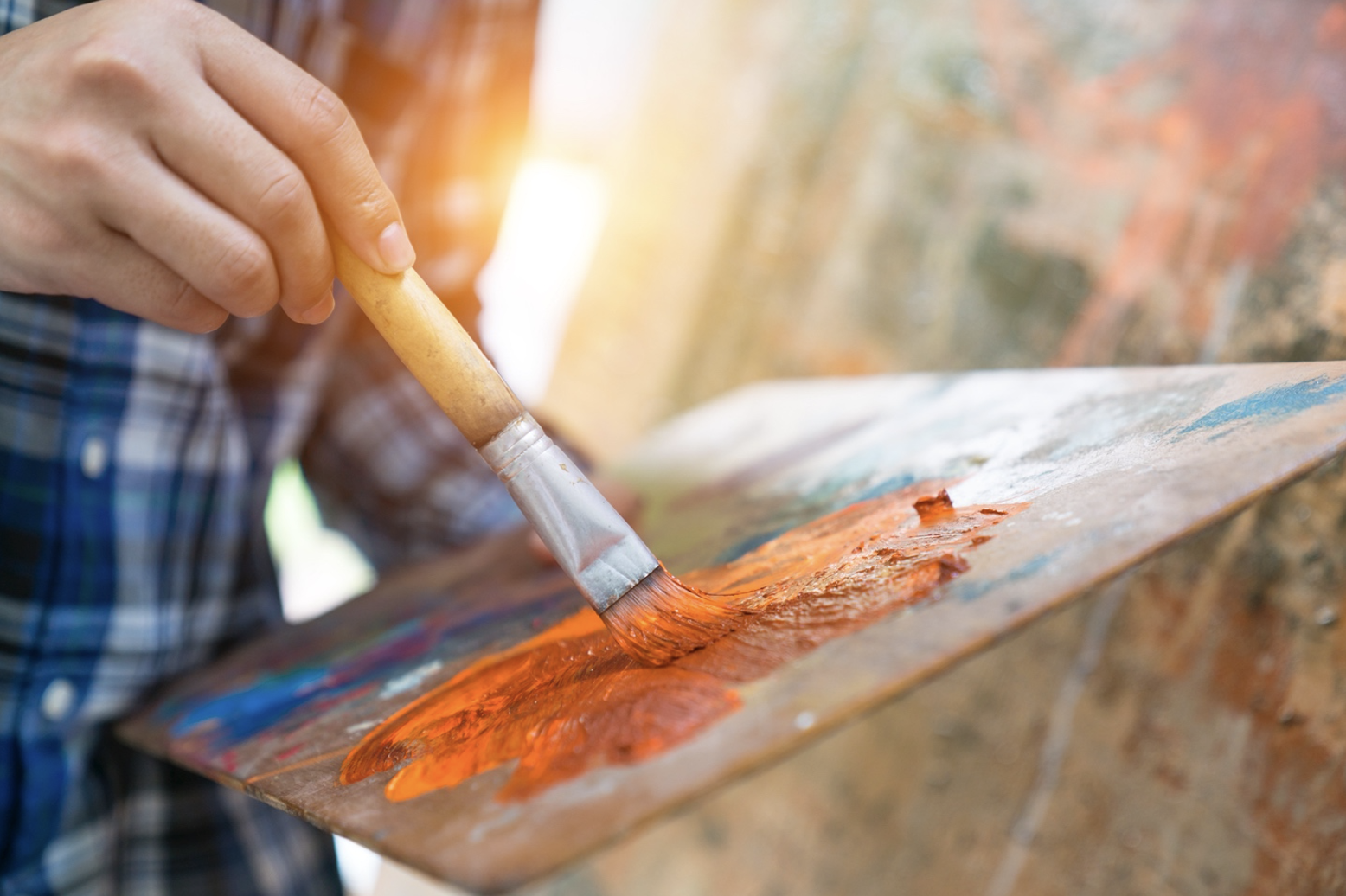 A man's hand is holding a paintbrush and using a palette