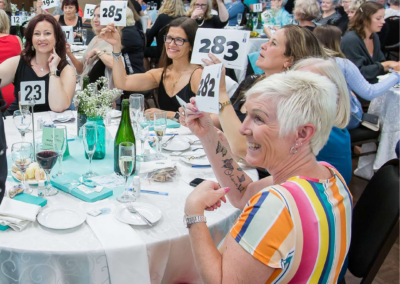 A group of women hold up auction numbers at the Handbags for Hospice Event
