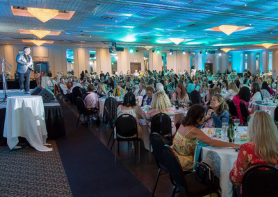 A large ballroom filled with people seated at round tables.