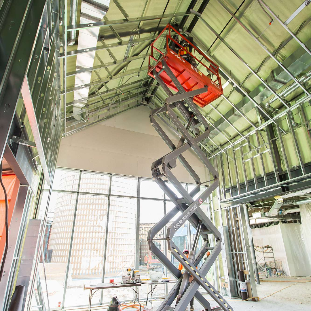 A worker is on scaffolding, working inside The Gies Family Centre