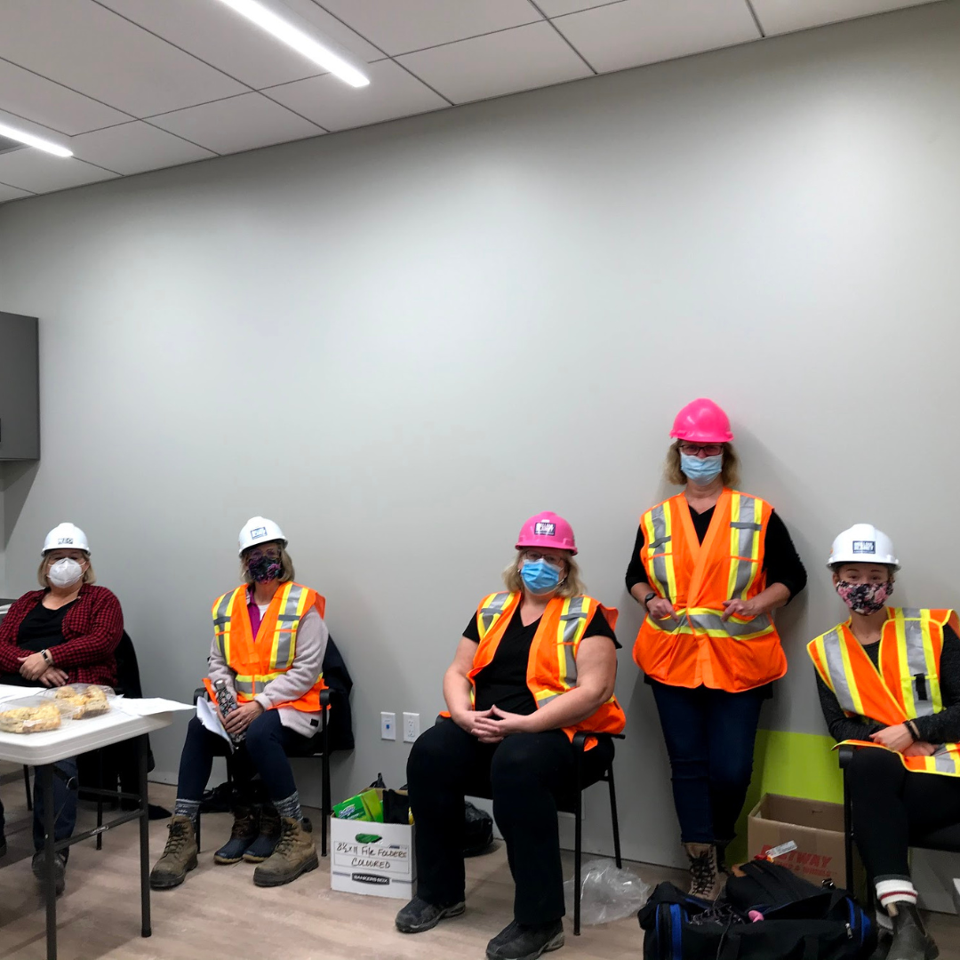 14 A group of HWR staff in orange vests and masks sit in the kitchen at The Gies Family Centre