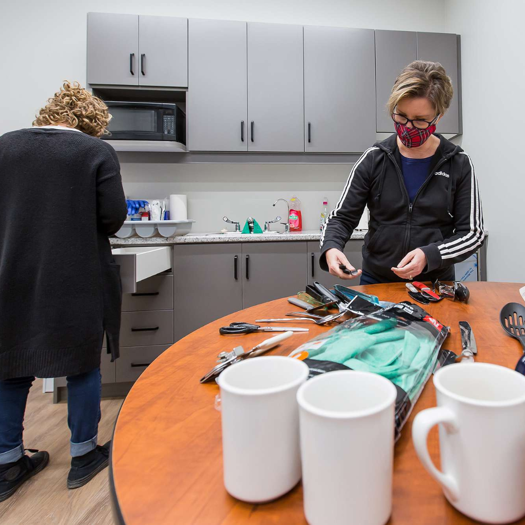 15 Two women unload cutlery and dishes in the kitchen at The Gies Family Centre