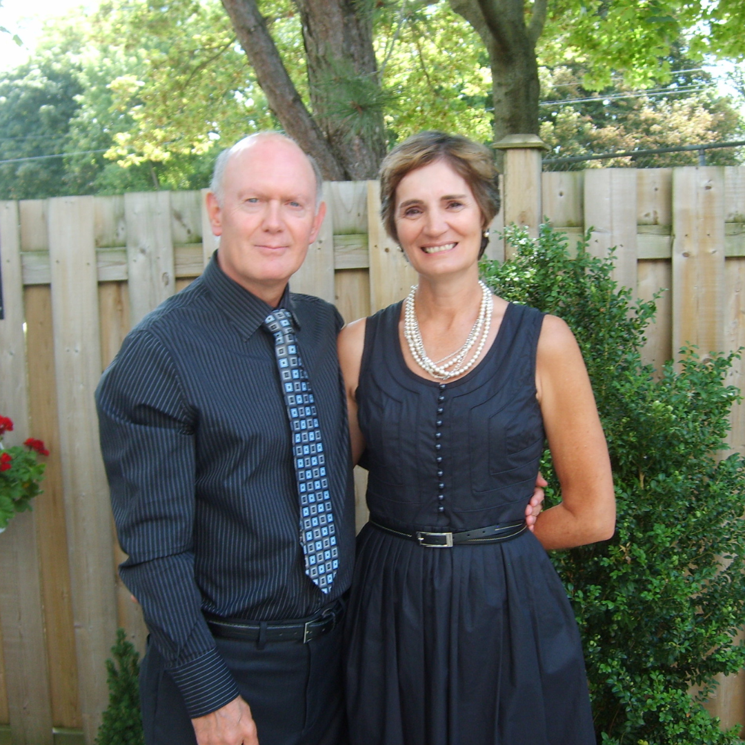 A man and woman pose for a photo. They are dressed up.