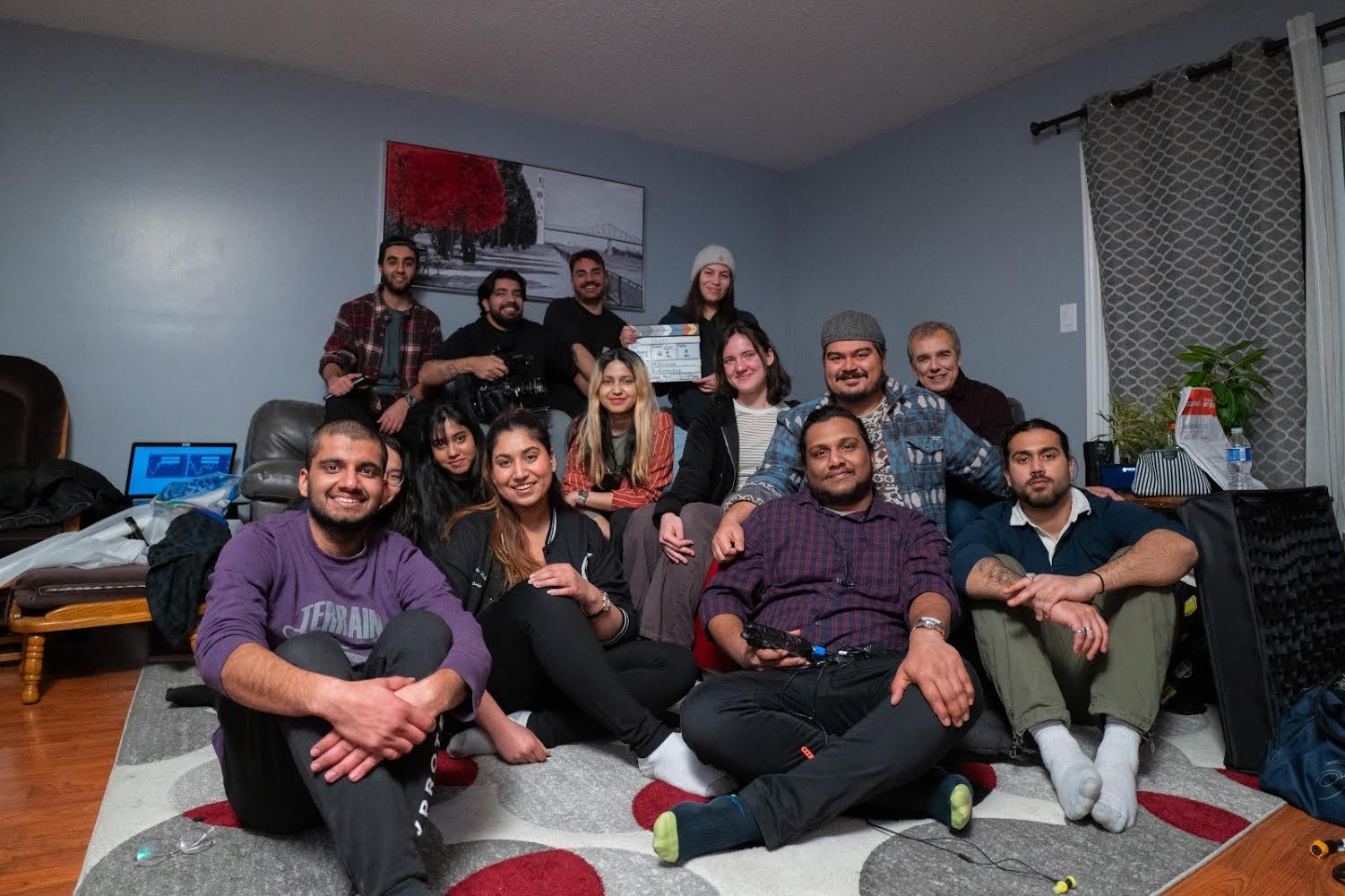 A group of people pose for a photo. Most of them are seated on the ground.